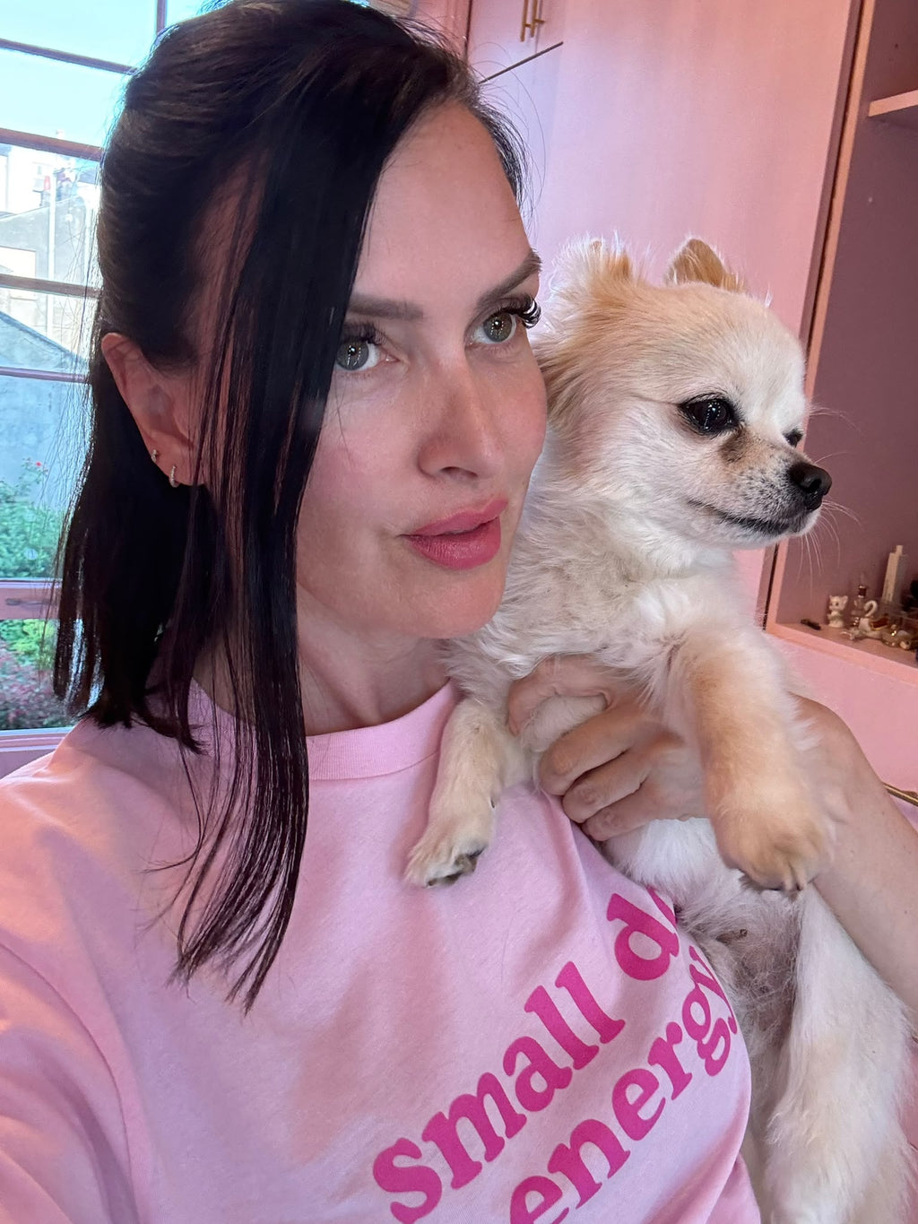 A customer wearing the pink small dog energy tee while holding a cream Chihuahua.