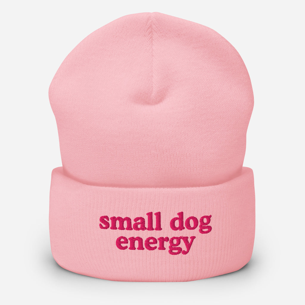 A light pink knit beanie hat with the phrase 'small dog energy' embroidered in dark pink on the front cuff, shown against a light gray background.